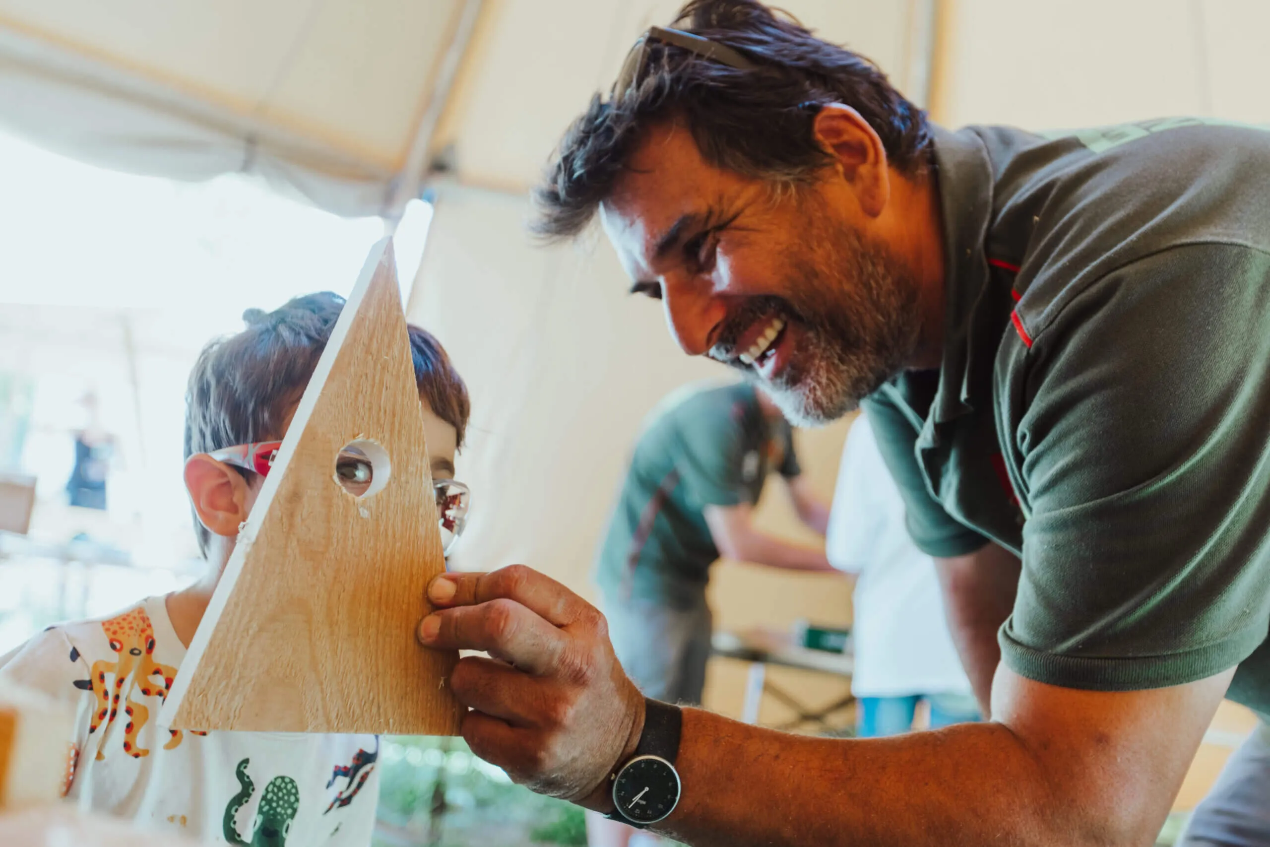 Eventfotograf München: Ein bestens gelaunter Handwerker präsentiert einem Jungen die Ergebnisse seiner Arbeit