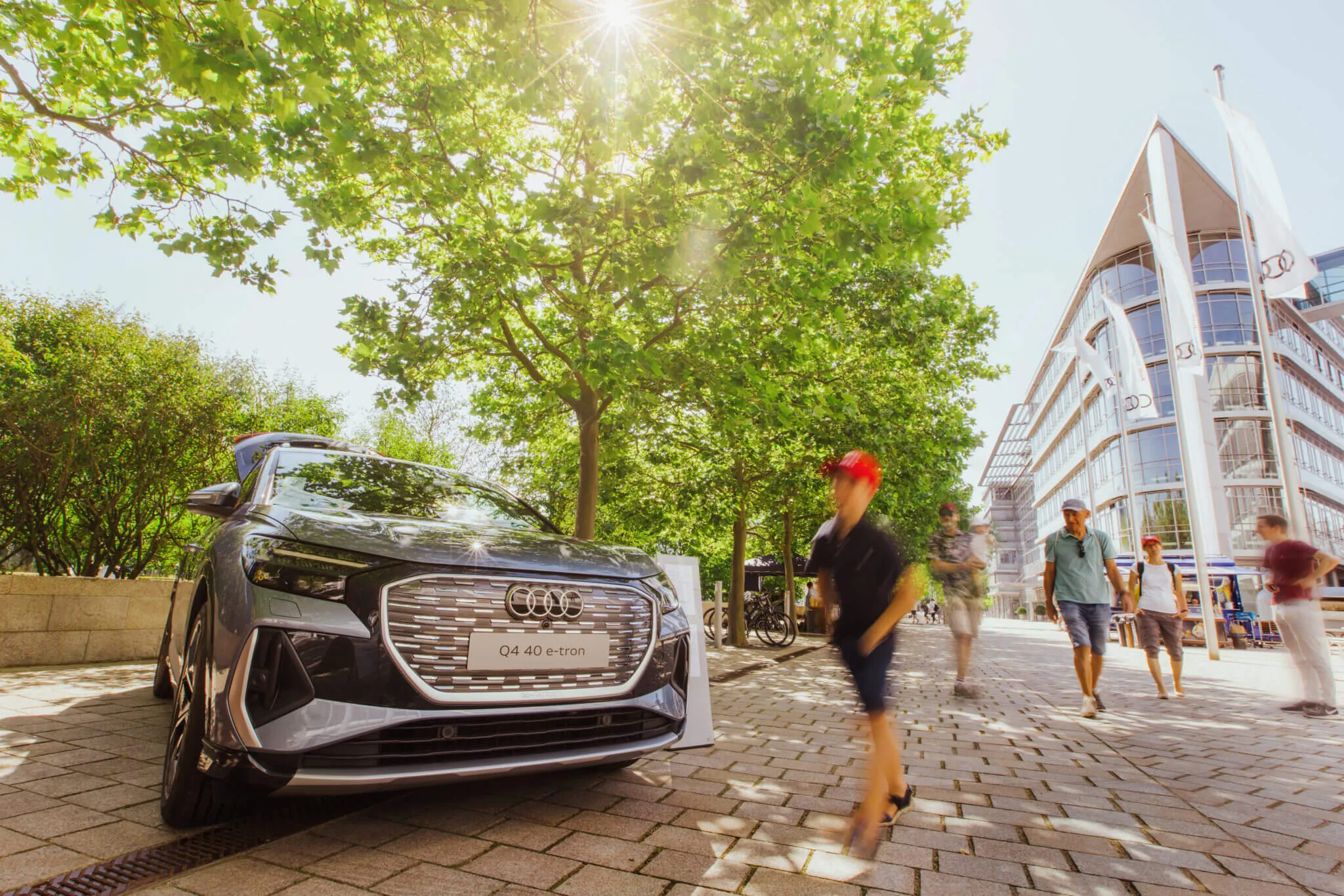 Eventfotograf München: Ein junge mit roter Mütze hurtet an einem schicken Auto unter grünem Blattwerk