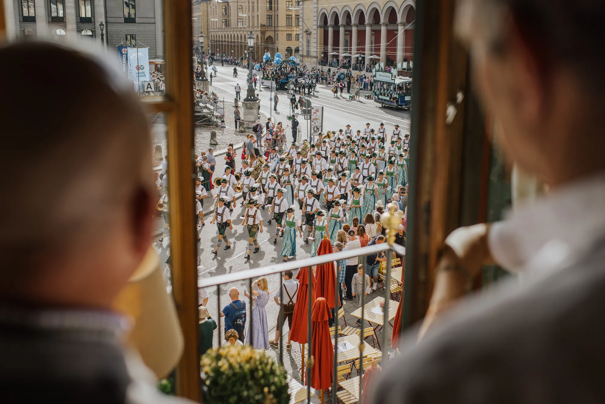 Eventfotograf München: Aus den Fenstern des Spaten Bräu in München bestaunen Personen einen Festumzug in München
