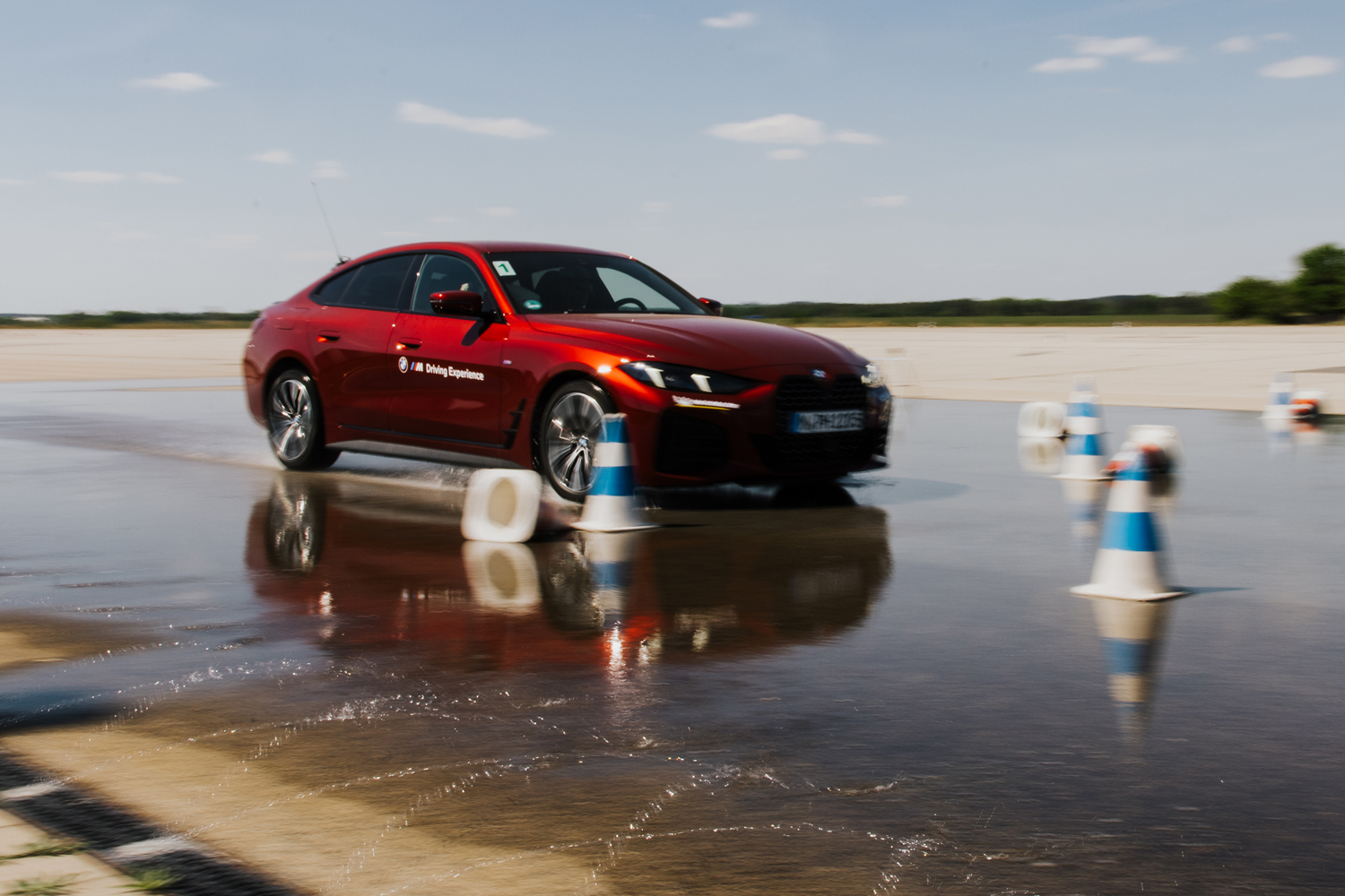 Roter Sportwagen driftet präzise auf bewässerter Trainingsfläche bei einem exklusiven Corporate Event in der Region München.