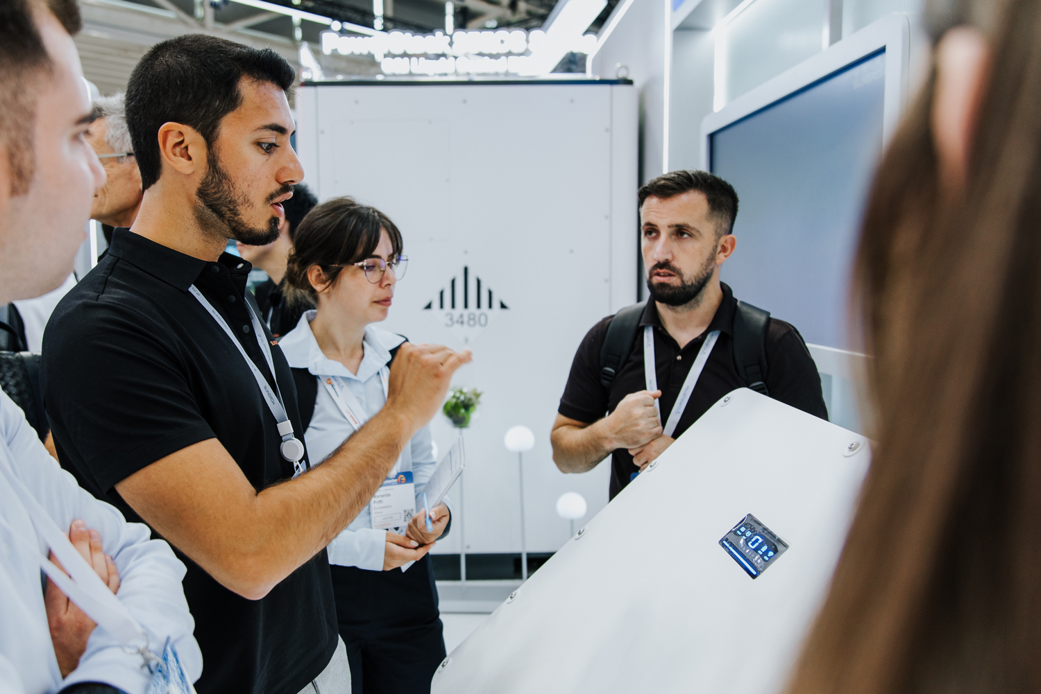 Messefotografie München: Eine Gruppe von Fachbesuchern im intensiven Informationsgespräch an einem modernen Messestand.