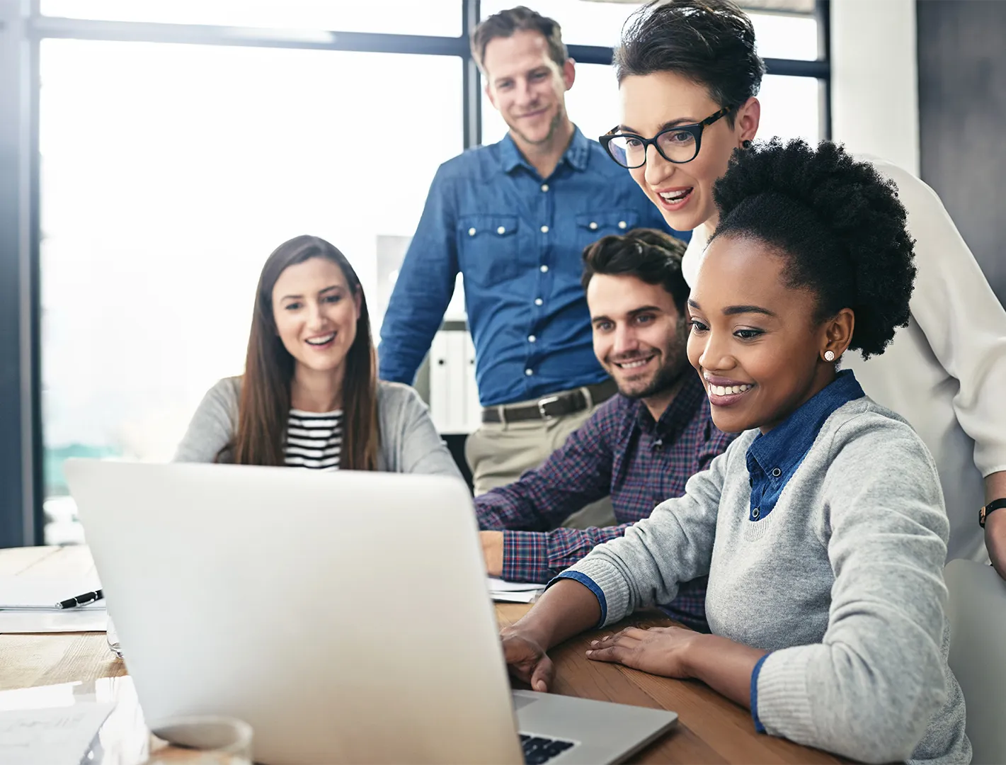 Team of coworkers gathered around a computer
