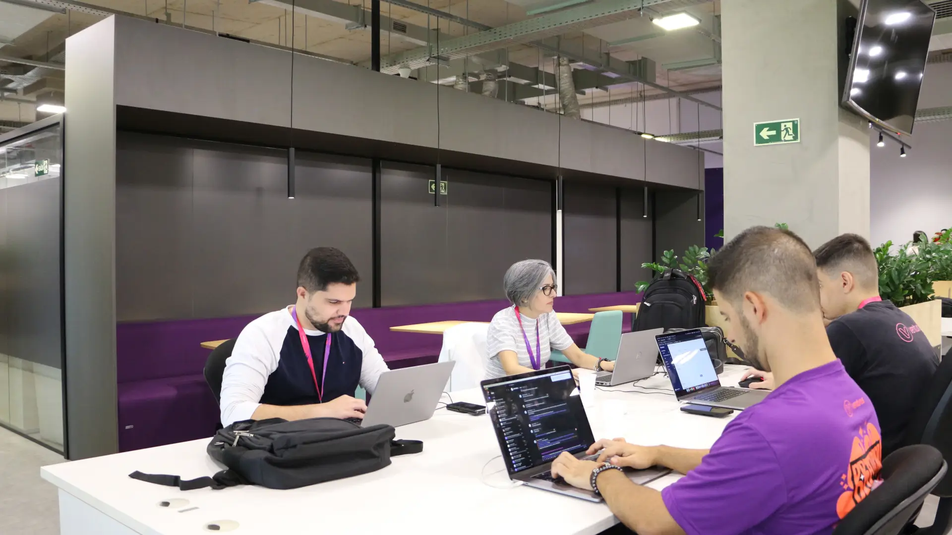 Várias pessoas sentadas em uma mesa com laptops