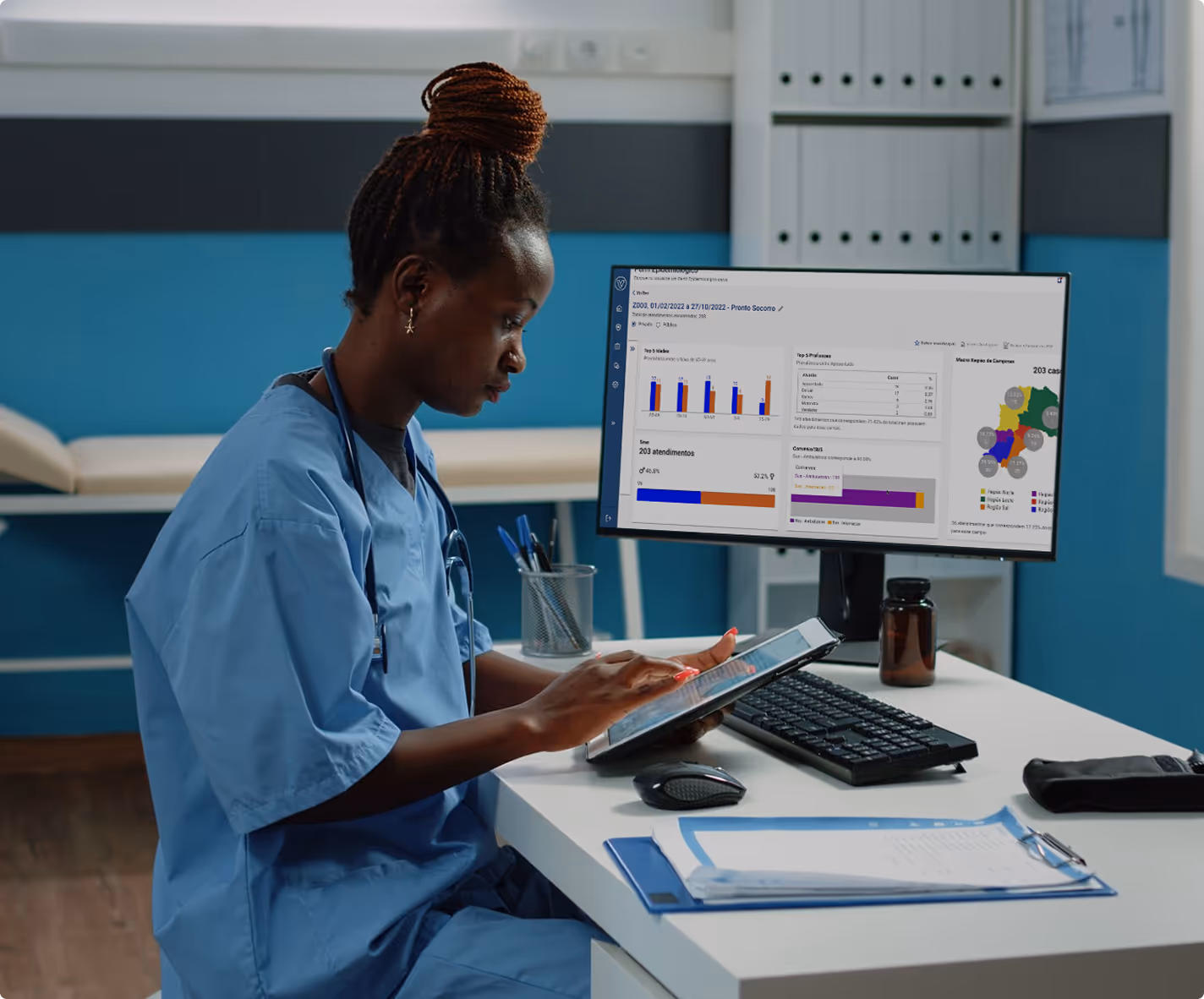 Mulher de uniforme médico sentada em uma mesa usando um tablet