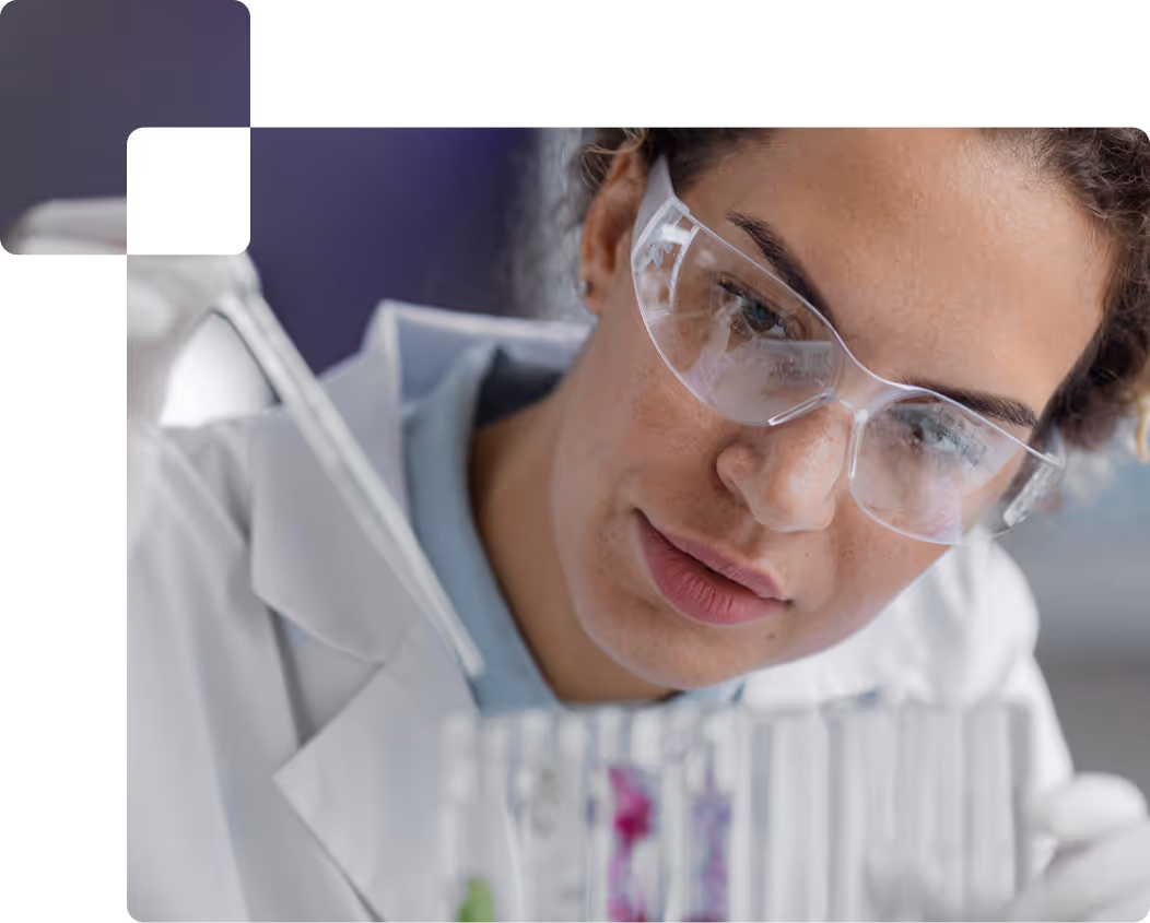Pesquisadora no laboratório com óculos de segurança e tubos de ensaio.