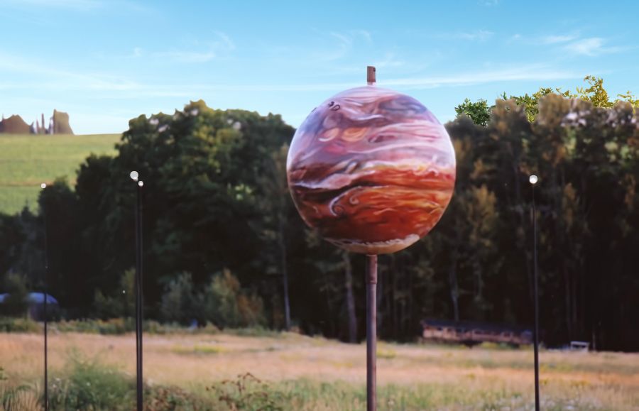 "Jupiter model with four moons at Maine Solar System Model, set in sunny aroostook county potato field is a picnic spot 
