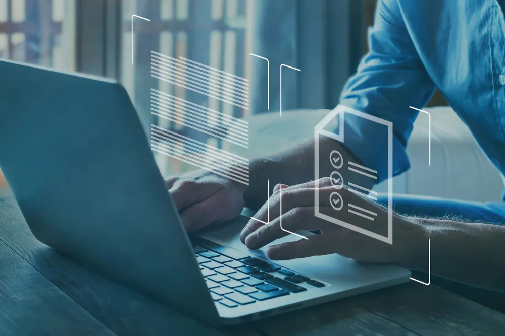 Image of person typing at a laptop. A virtual checklist is floating above the user's hands.