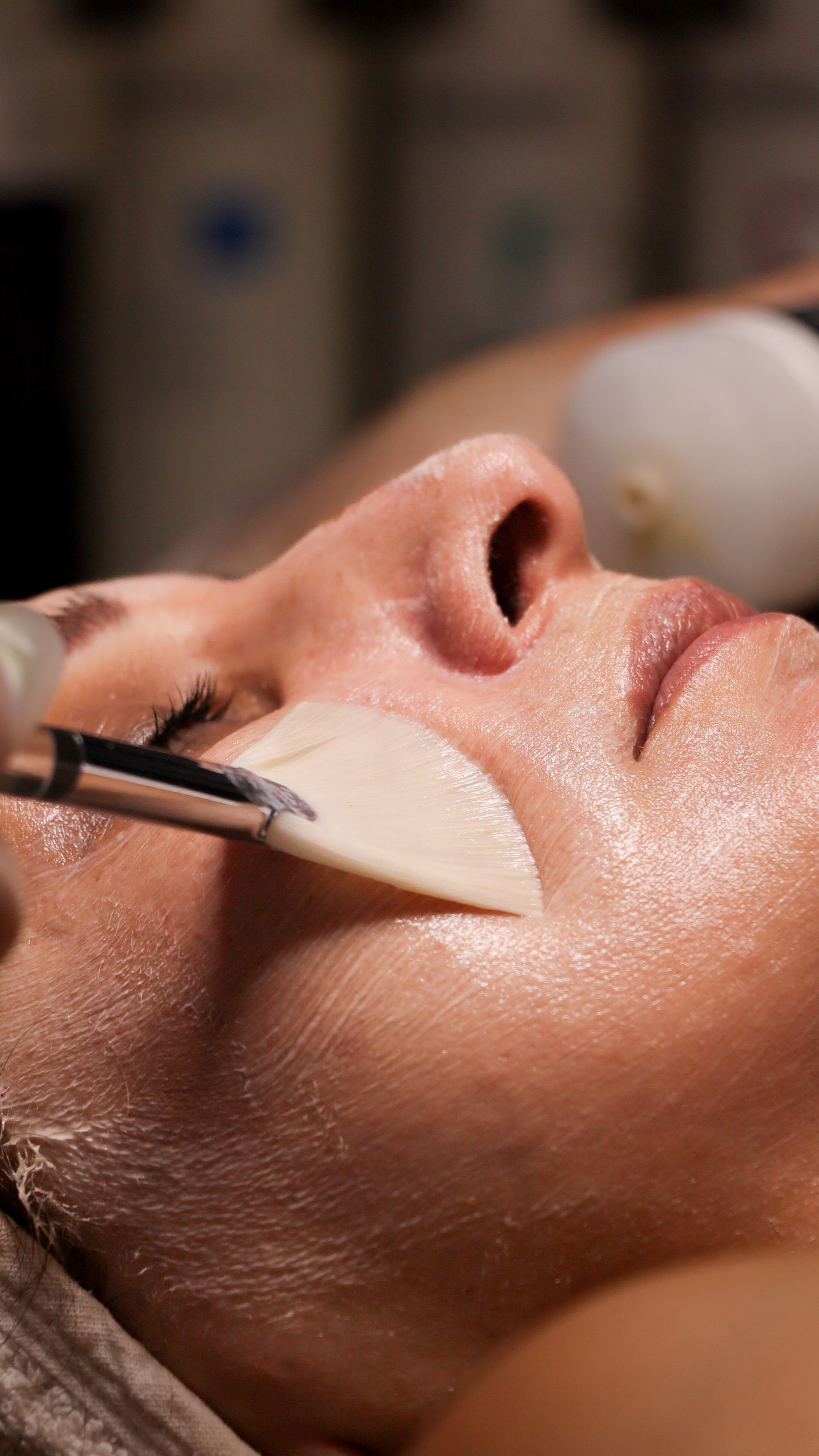 DEJ BioStim peel solution being applied to a client's face with a fan brush