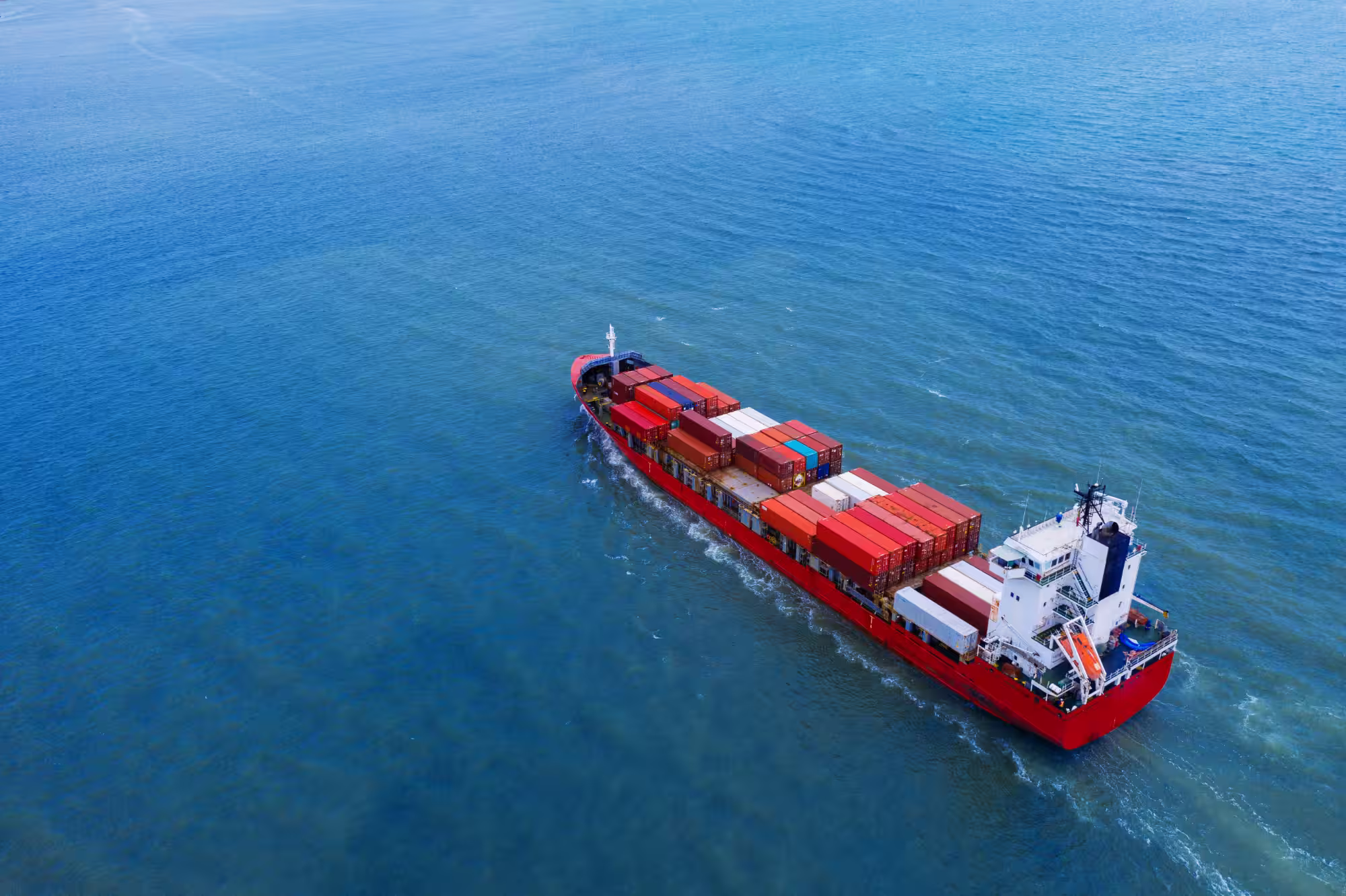 Großes Frachtschiff, das unter klarem Himmel über offenes Wasser fährt.