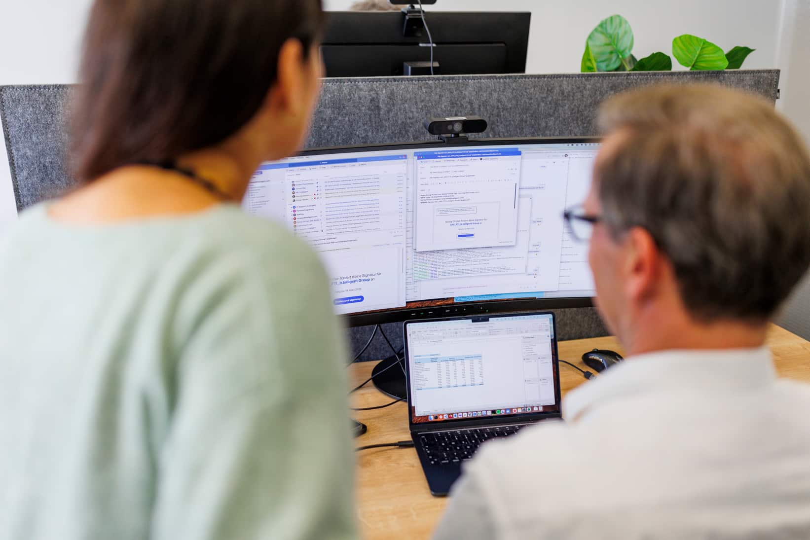 Two colleagues sitting side by side in front of a screen.