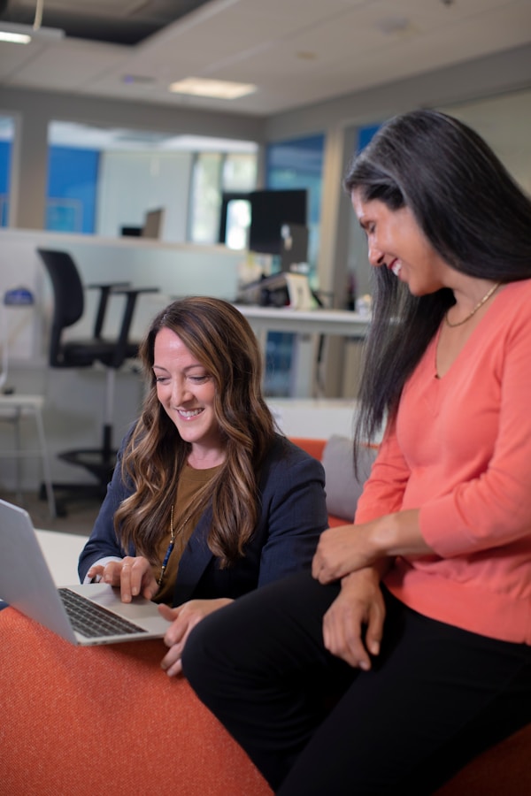 Two women working and laughing on laptop