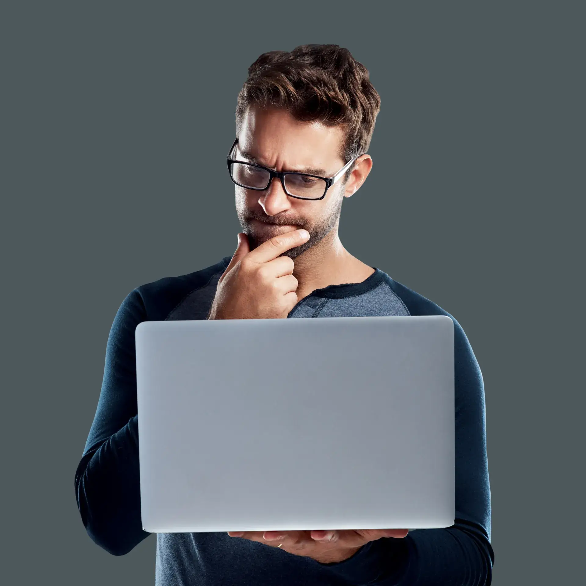A man in glasses is looking at a laptop.