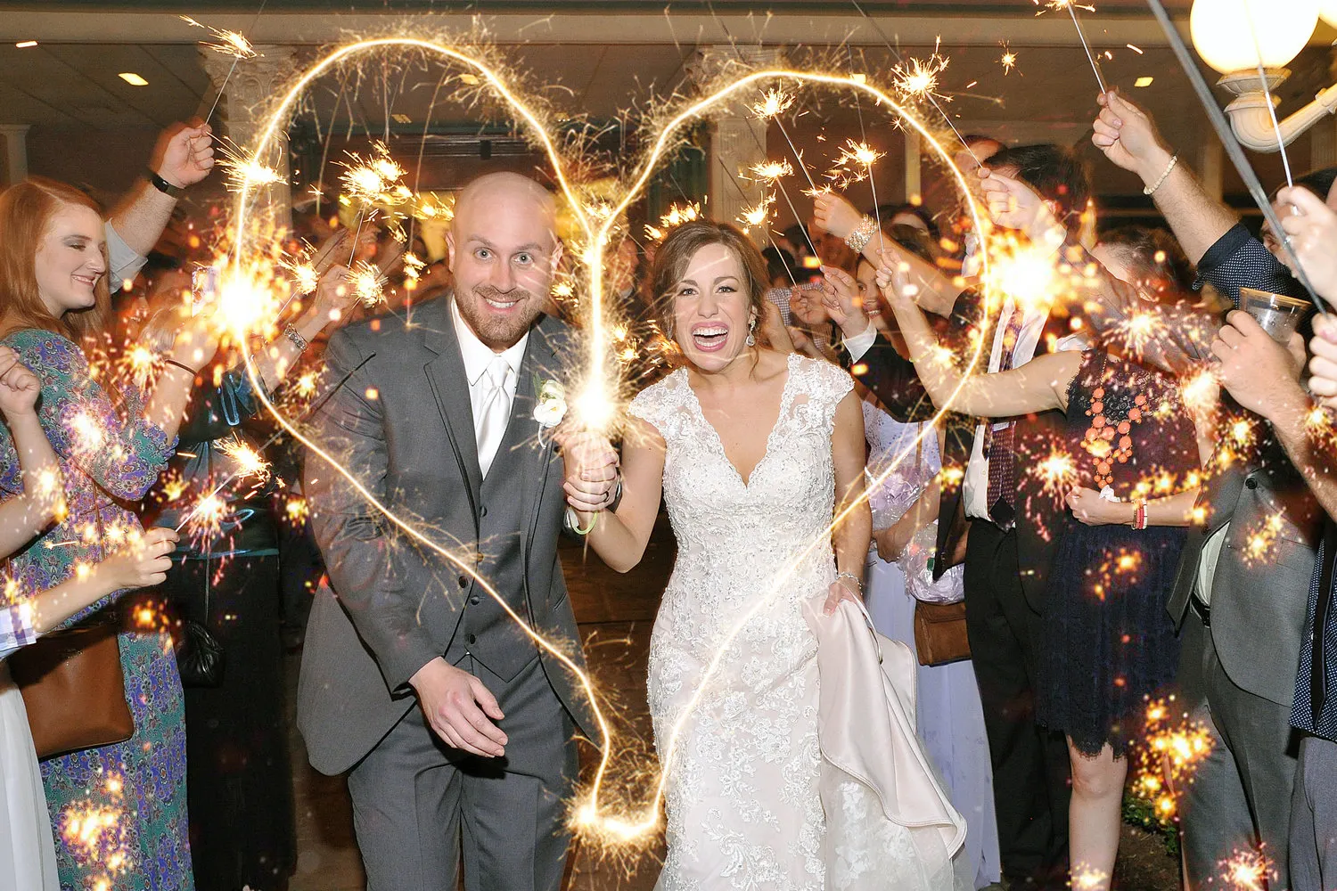 A newly married couple celebrating with sparklers and making the shape of a heart with the sparklers
