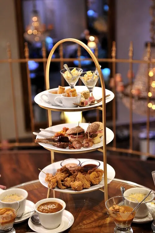Indoor event with people socializing around tables and hanging glass globes with lit candles creating a warm, festive ambiance.