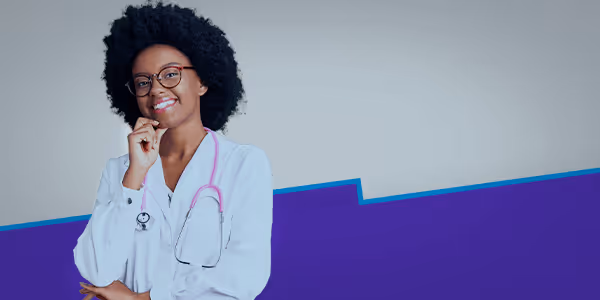 Smiling female doctor with glasses and stethoscope, standing with hand on chin against blue background.