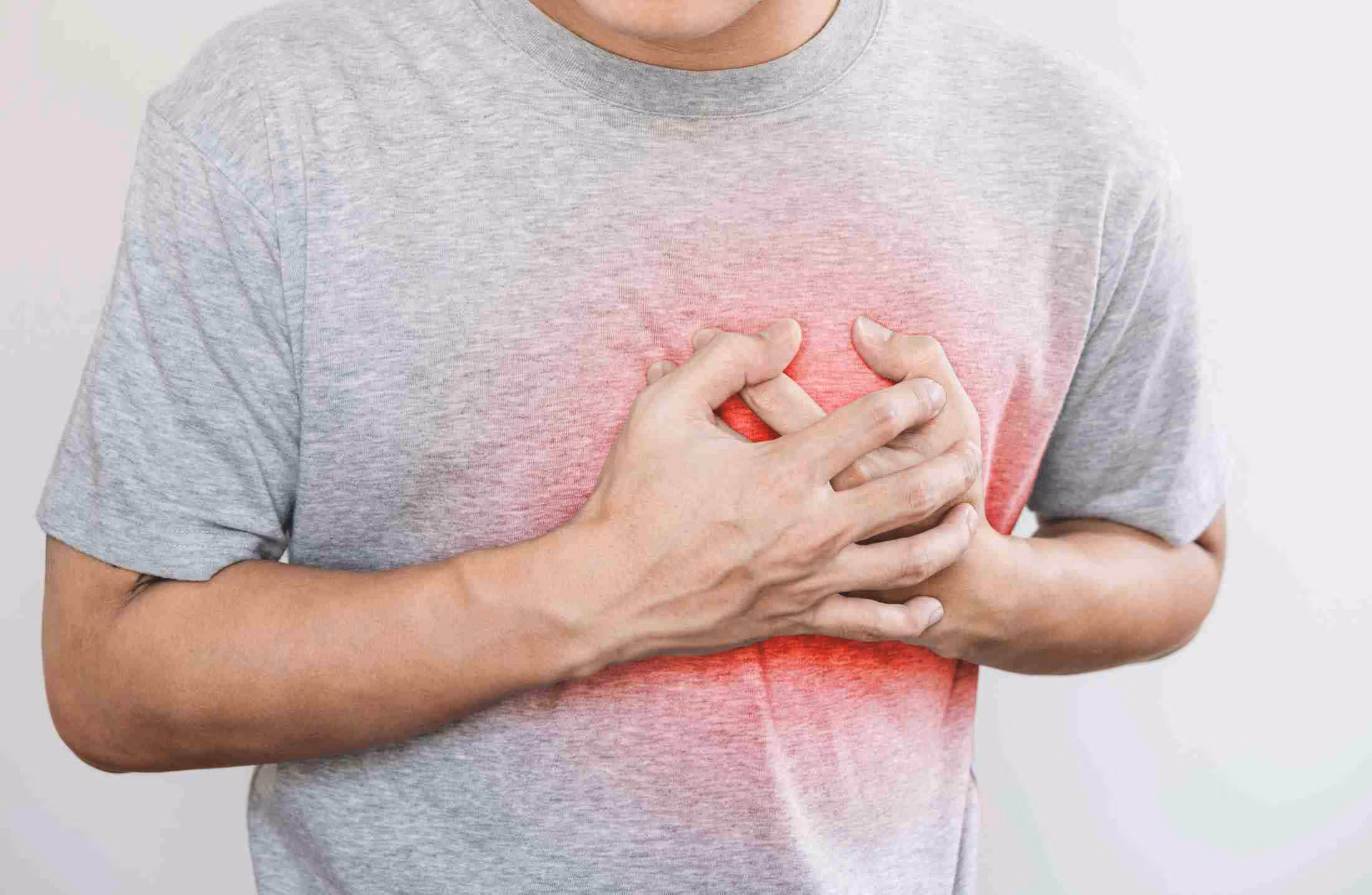 Person clutching chest with both hands showing pain or discomfort in the heart area.