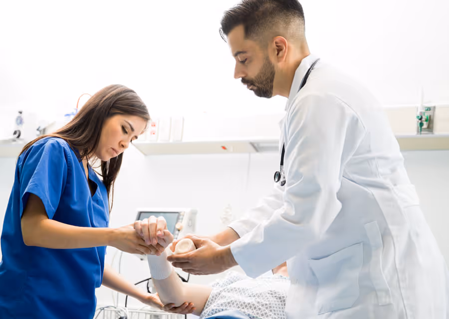 Doctor applies a wrist cast to a patient with nurse assisting in a medical clinic.