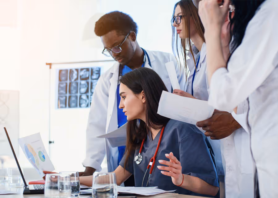 Group of diverse doctors reviewing charts and documents together in a medical office.