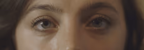 Close-up of a person's eyes with long eyelashes and light brown irises.