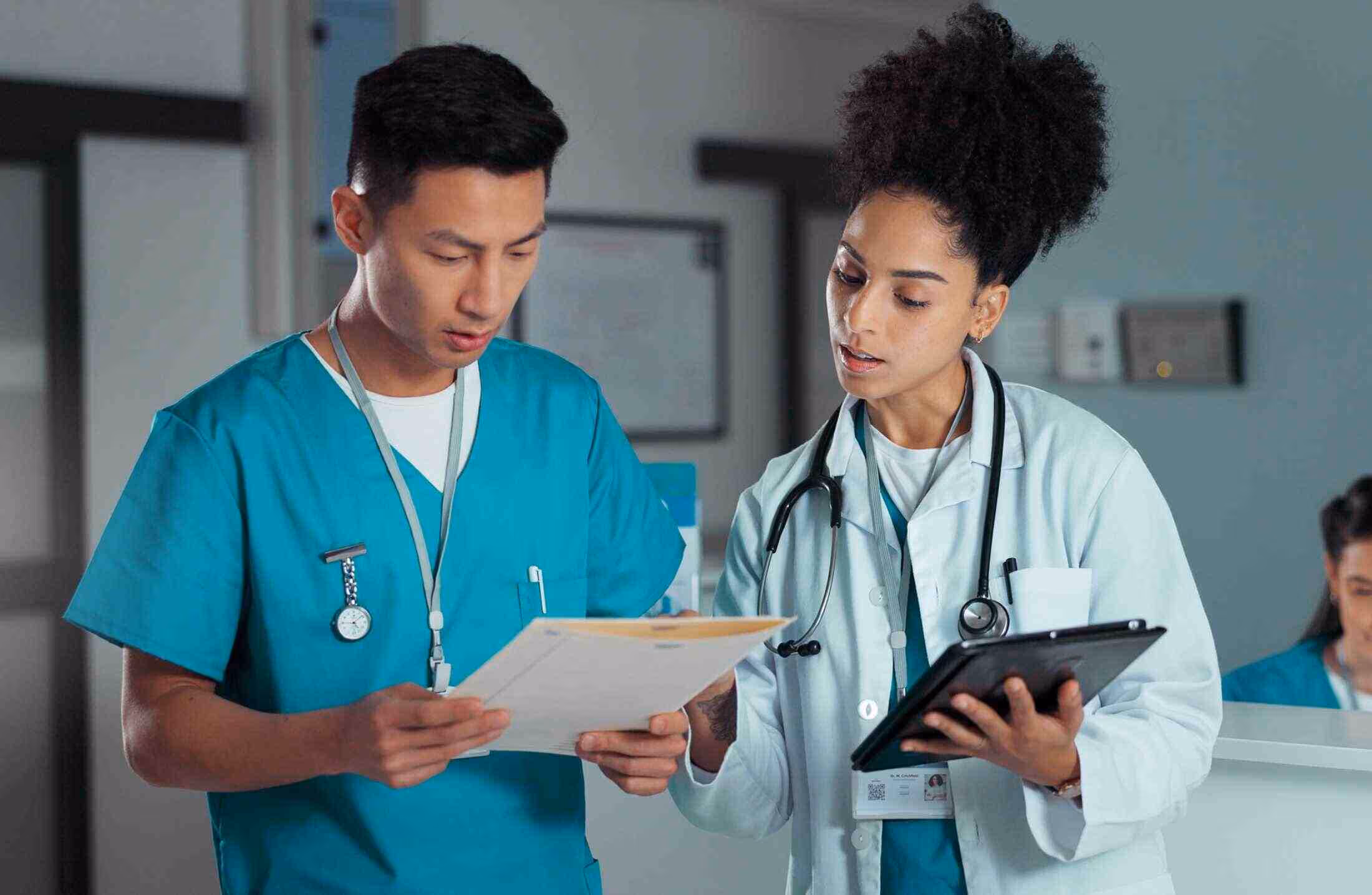Two medical professionals reviewing documents together in a clinical setting.
