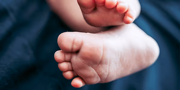 Close-up of a baby's feet resting against a dark fabric background.