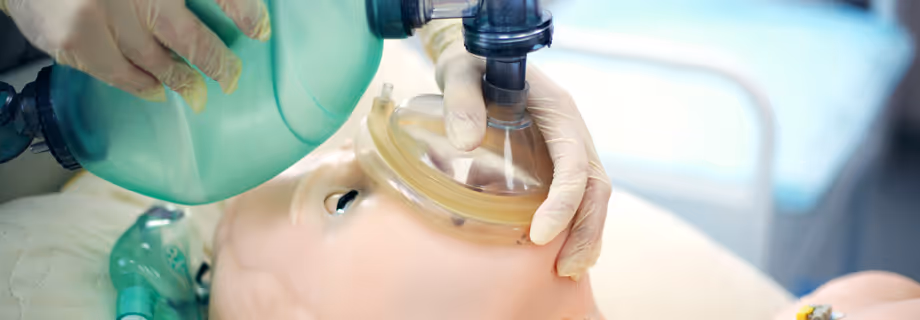 Medical professional using a manual resuscitator on a patient lying in a hospital bed.