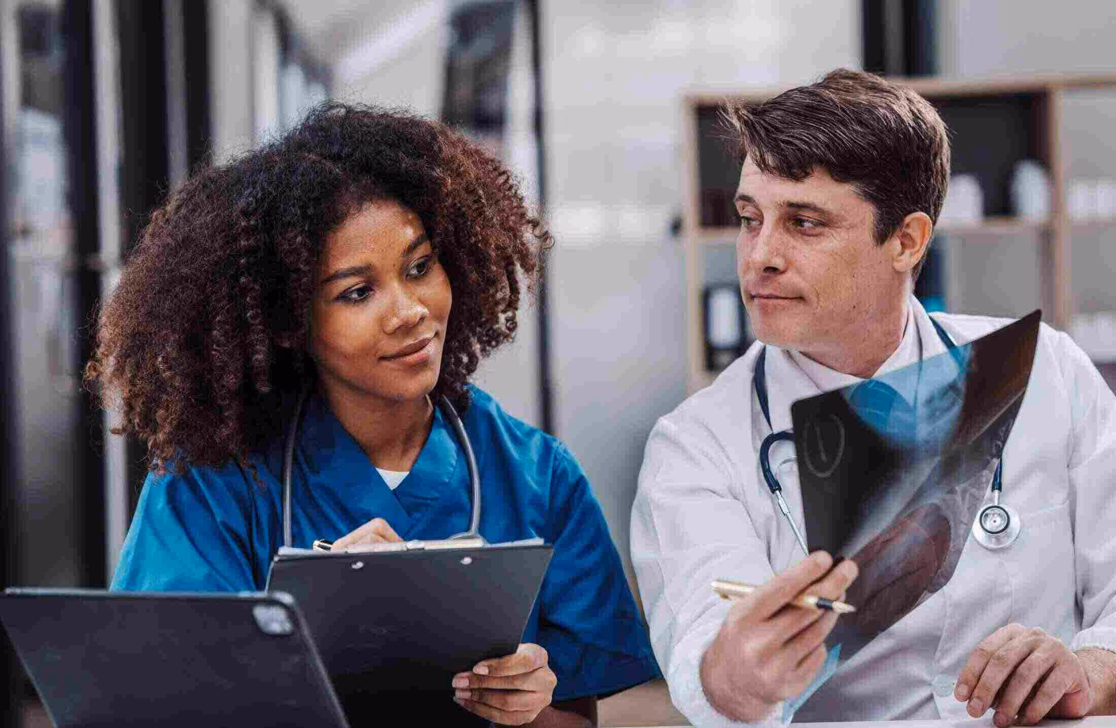 Two doctors reviewing and discussing an X-ray image in a medical office.