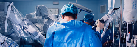 Medical team operating with robotic surgical equipment in a sterile hospital environment.