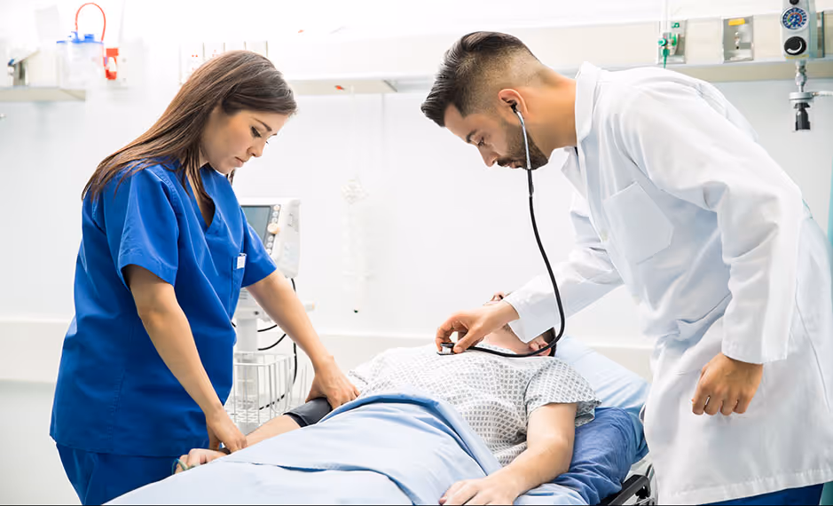 Doctor and nurse examining patient lying on hospital bed in a clinical setting.