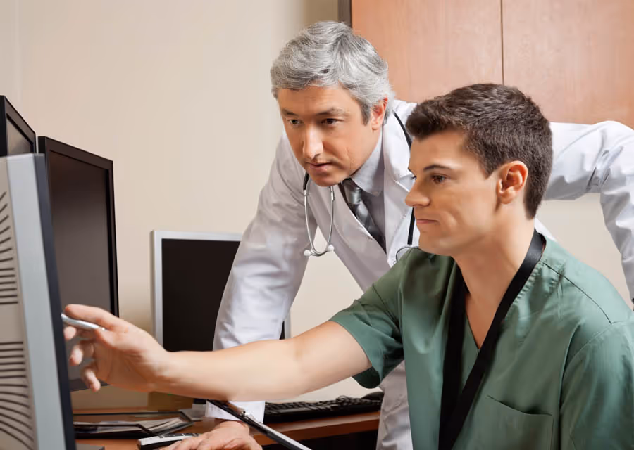 Two doctors in a medical office reviewing information on a computer screen together.