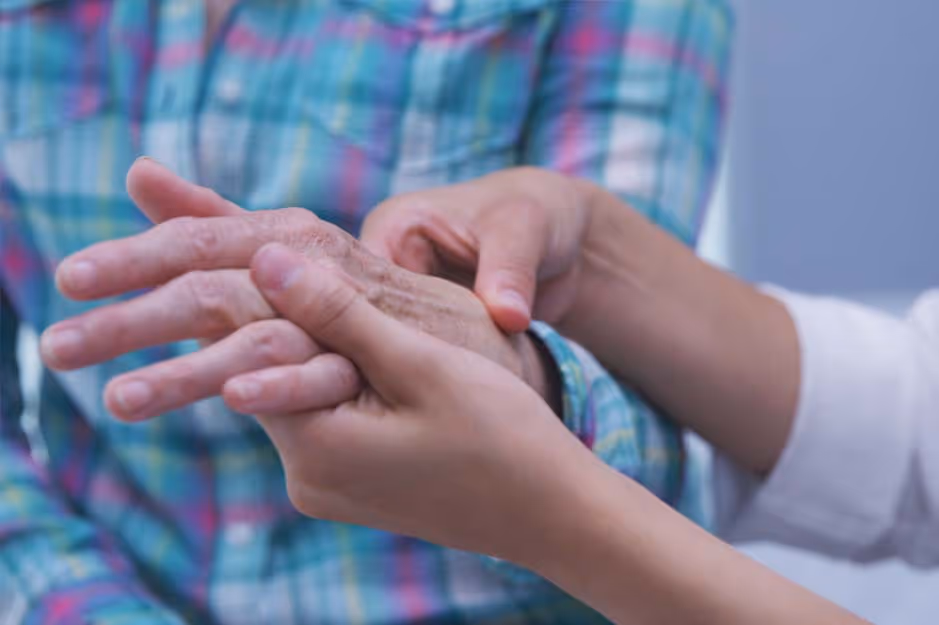 Two hands gently holding an elderly person's hand, suggesting care and support.
