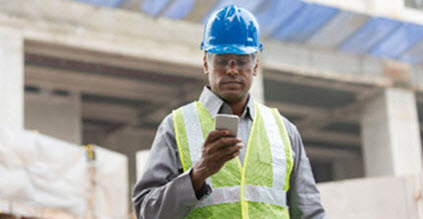 Man consulting his phone on a construction site
