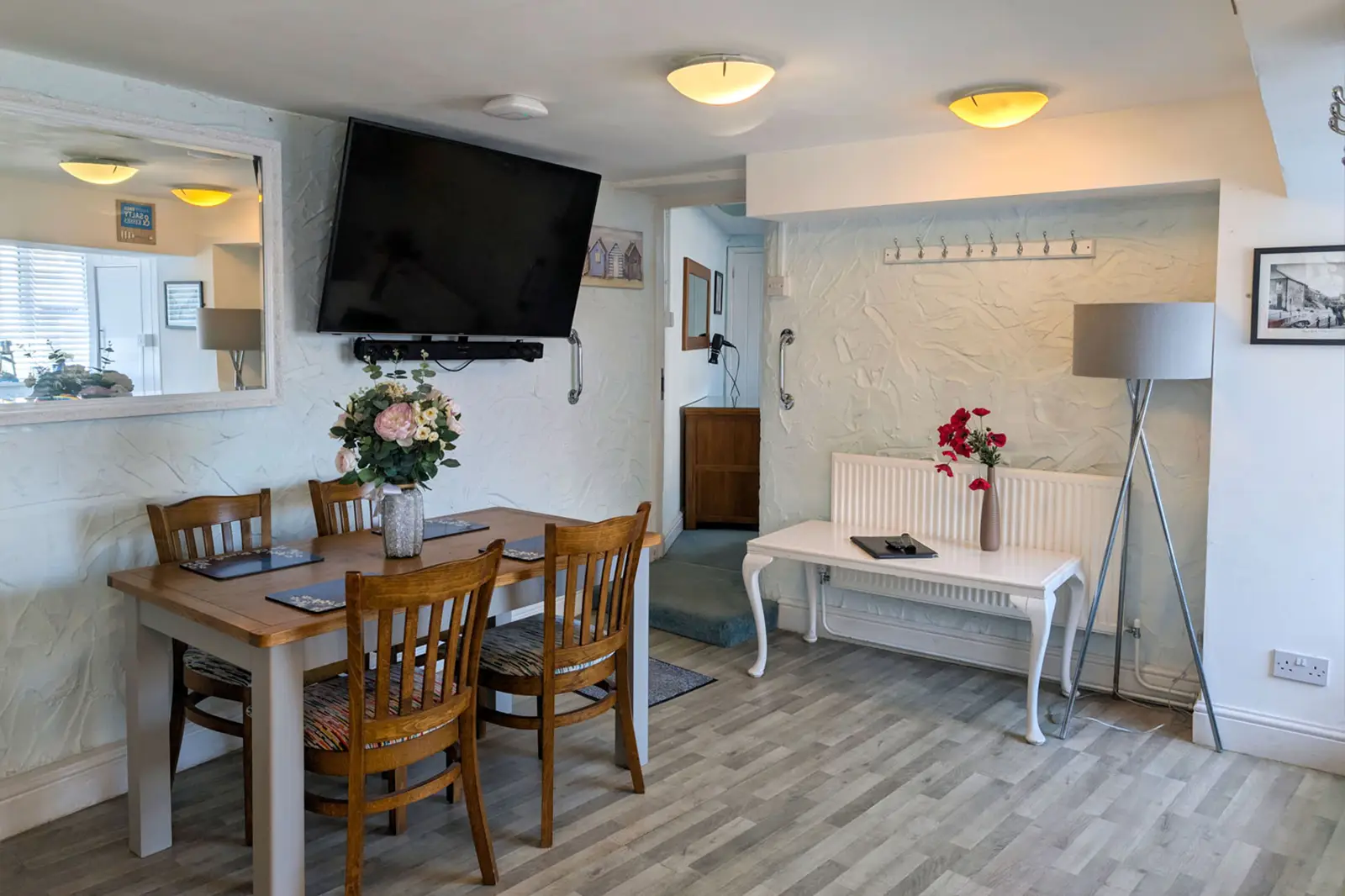 A dining room with table for four and a large flatscreen TV fitted to the wall