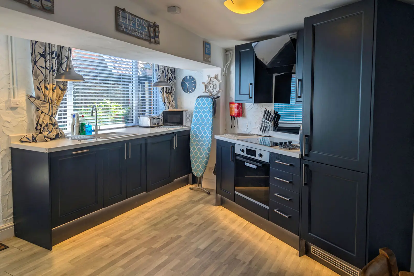 A roomy kitchen with dark blue cabinets and low lighting accent