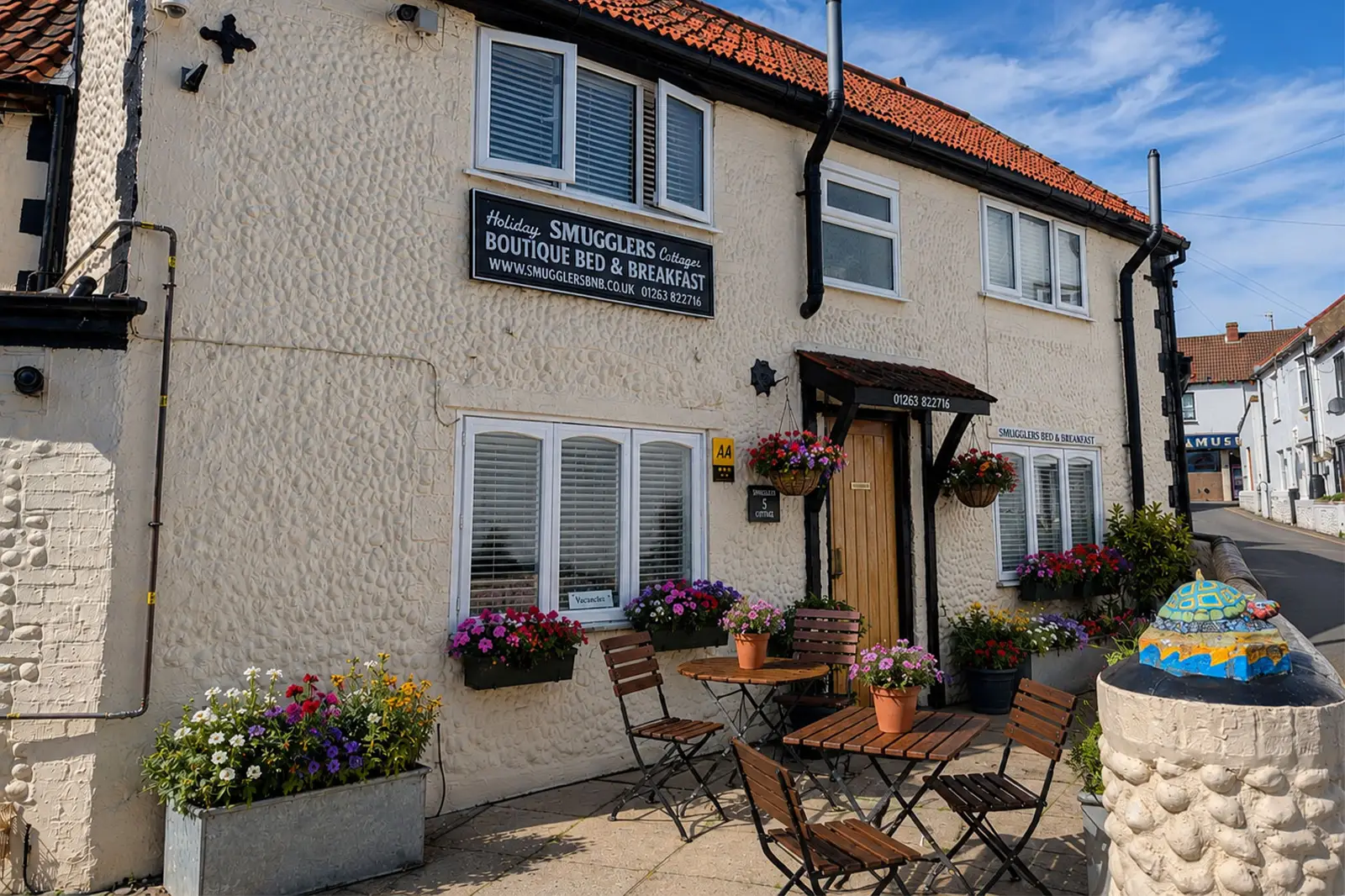 An exterior shot of Smugglers Bed & Breakfast with blossoming flowers on a bright and sunny day