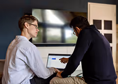 Jannis Timm führt ein Kundengespräch und zeigt Webdesign Beispiele auf seinen Laptop