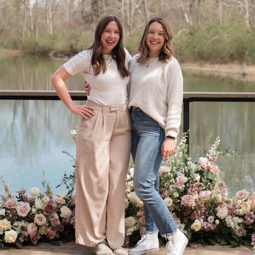 Kristin Martin and Katherine Katherine Martin, Founders of Duet Floral Studio, Stand Smiling In Front Of Floral Installation at the Conservatory at Evergreen