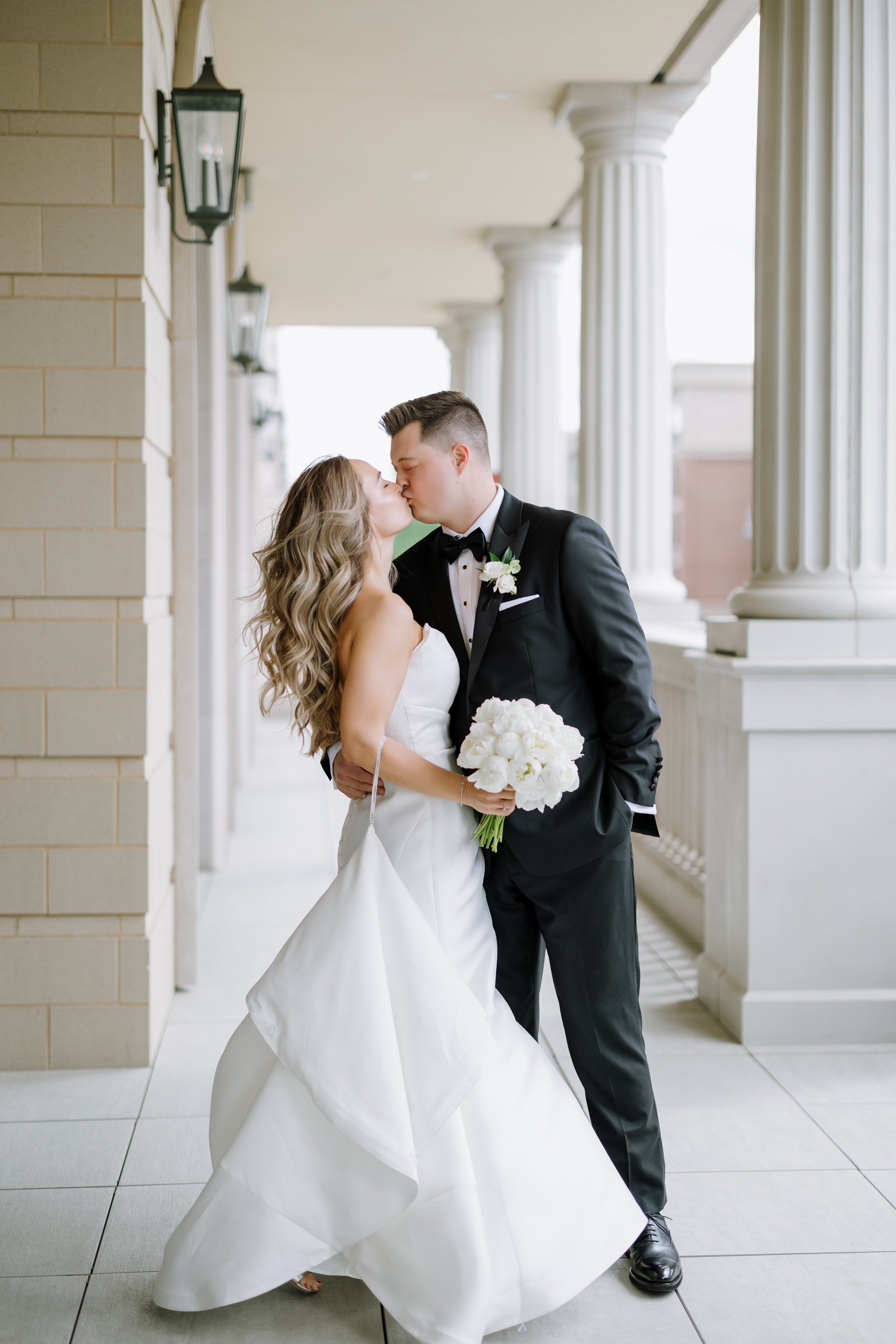 bride and groom kissing and holding wedding flowers at hotel carmichael