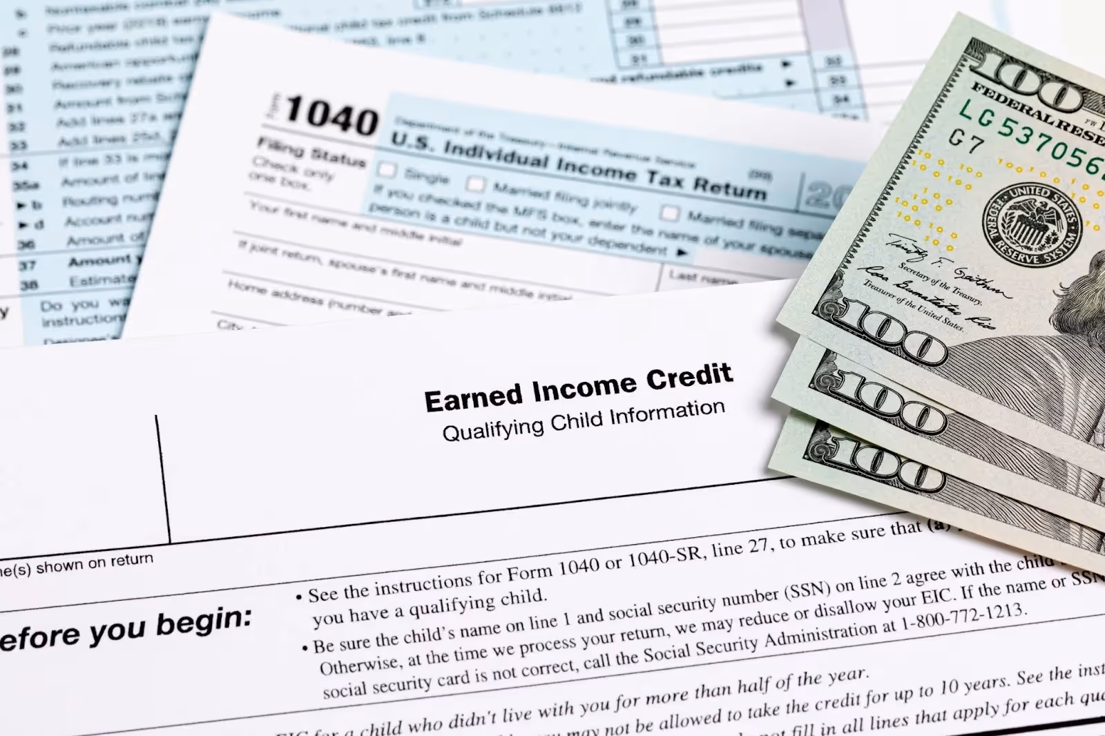 Photograph of tax forms and three 100 dollar bills