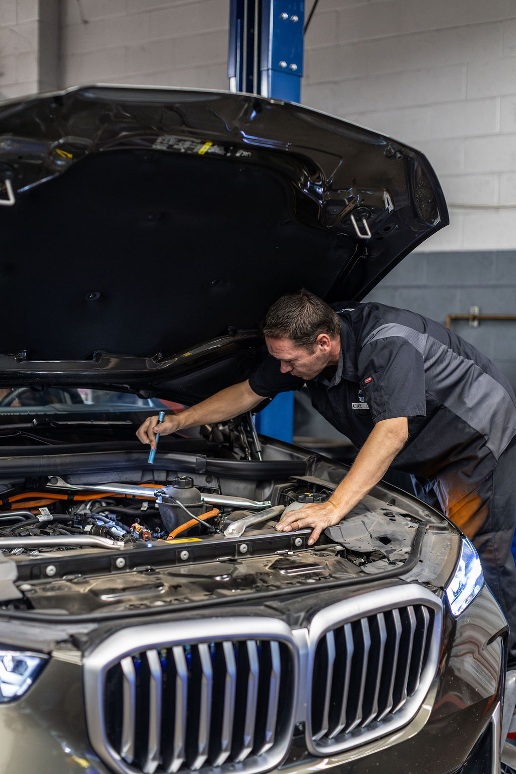 A Car Life technician inspecting a vehicle's engine
