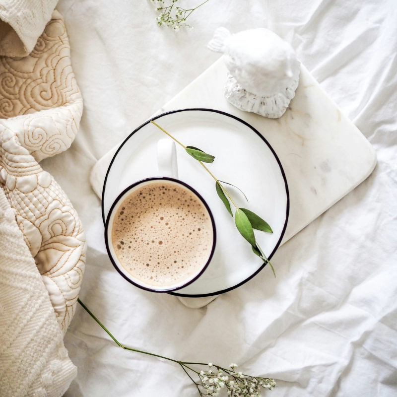 flatlay of coffee on white bedding