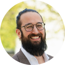 Smiling man with a beard and glasses wearing a suit jacket and white shirt outdoors - Co-Founder & CTO - Dr. Robin Bayer