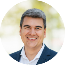 Smiling man with short hair wearing a white shirt and navy blazer outdoors - the Co-Founder & CEO - Dr. Reza Esmaillie