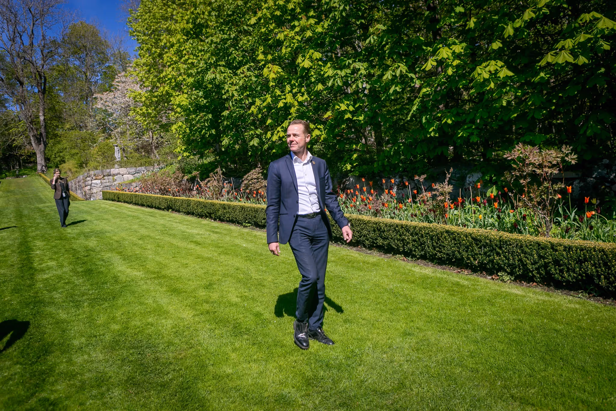 Mann som går utendørs på en grønn plen i fint vær 
