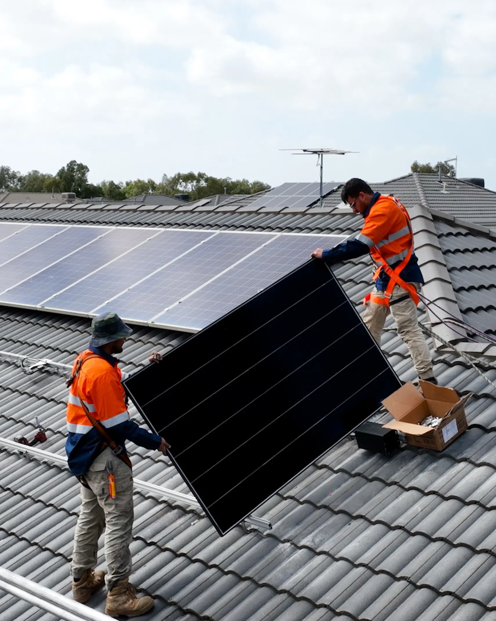 Essential Solar installers carrying solar panel on roof
