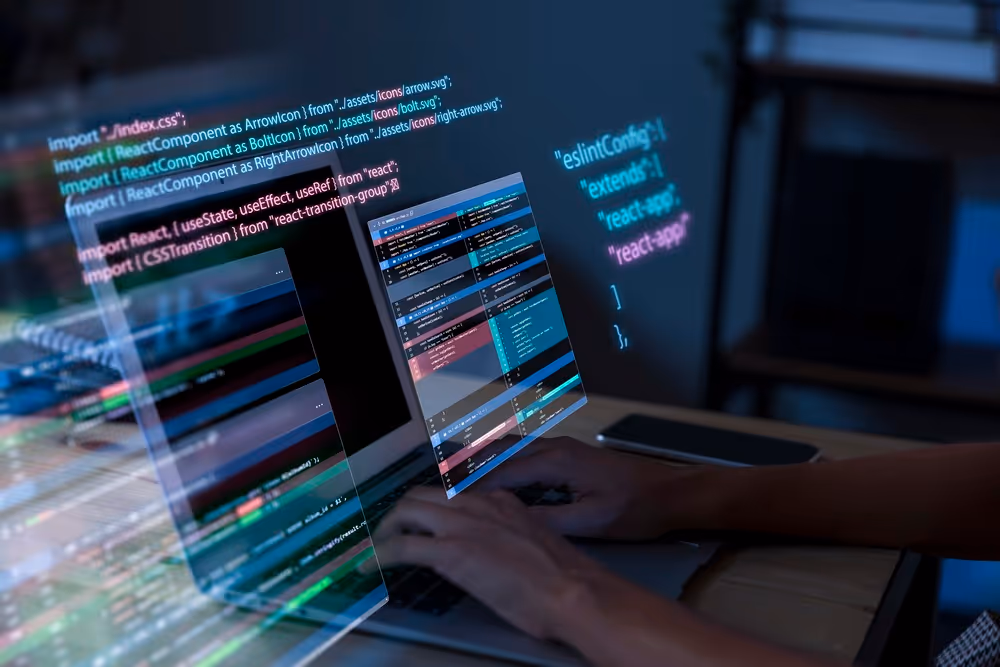 Persona escribiendo código en una computadora portátil con fragmentos de código en JavaScript y React visibles en pantallas superpuestas.