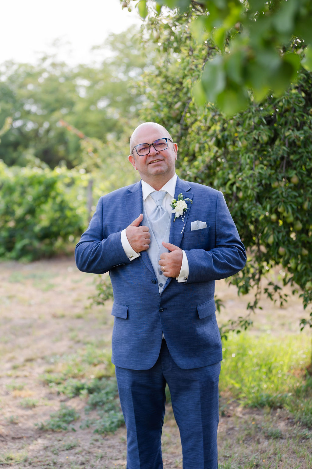 vőlegény kék öltönyben és fehér gombdísszel