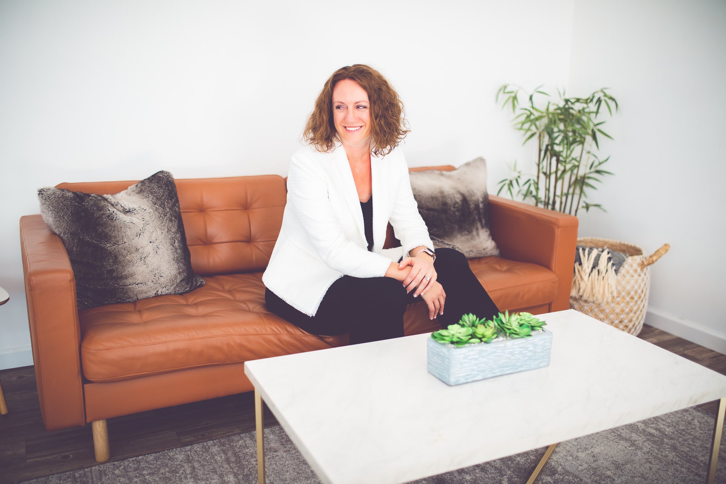 Elissa Kelly, PCC, seated on a couch in her office