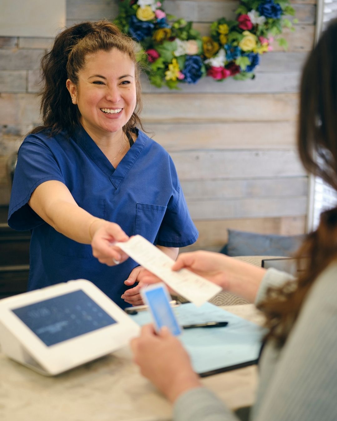 Medical receptionist smiles as she accepts payment from customer