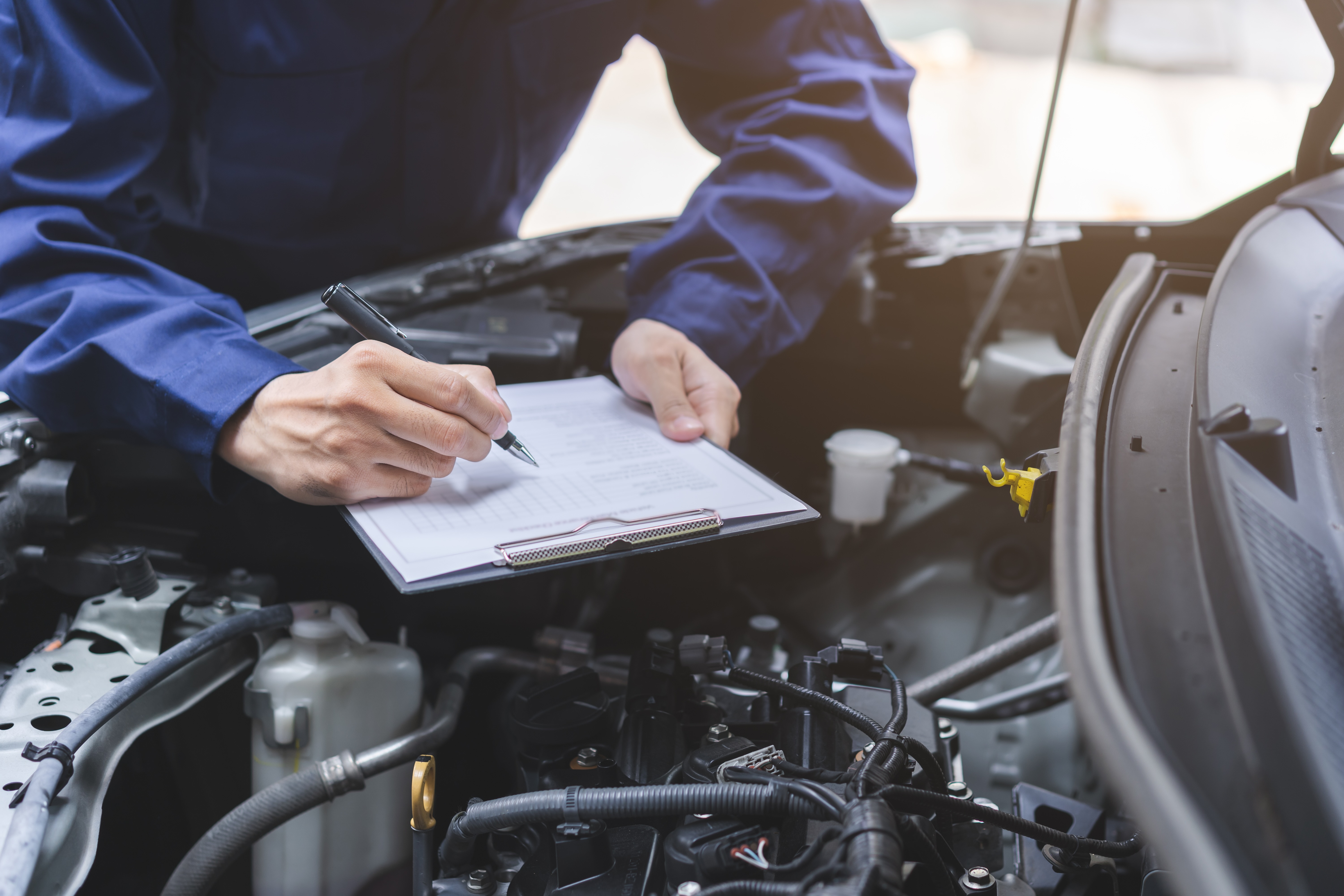 Man doing a routine check while looking under a cars hood